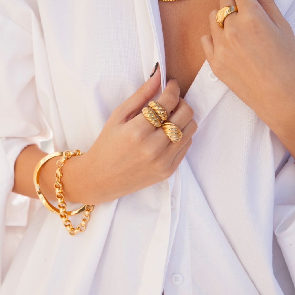 A lady wearing gold rings, necklaces, and bracelets.